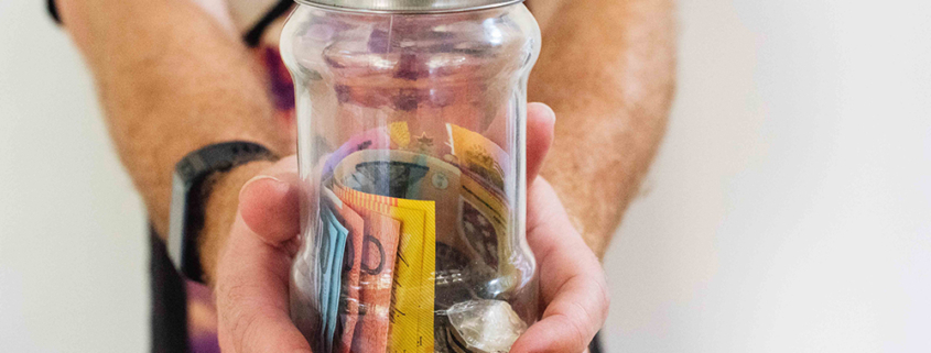 person holding glass jar filled with Australian money